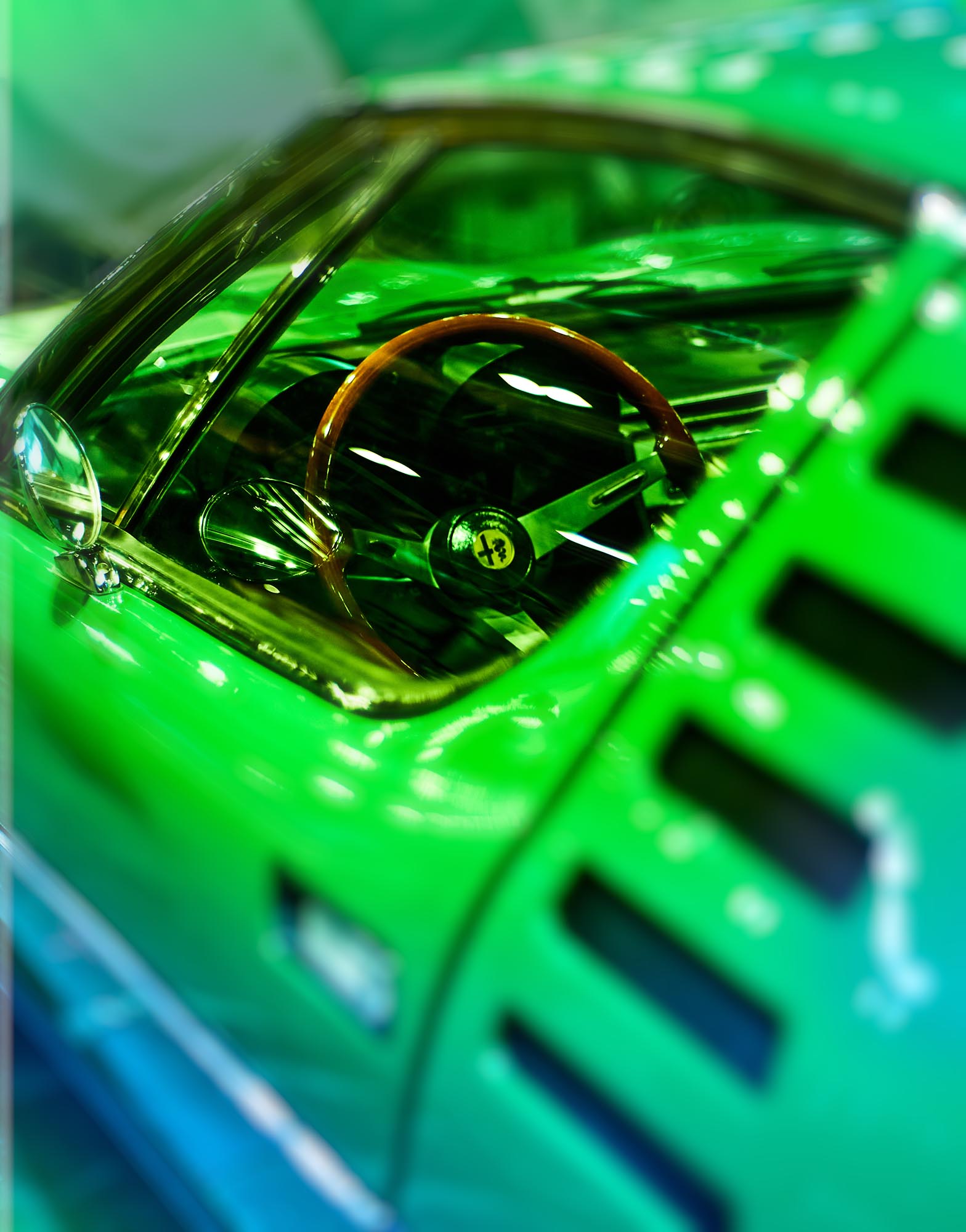 Detalle de faros delanteros dobles de un Alfa Romeo GT Junior clásico bajo luz verde ambiental - Frameburn