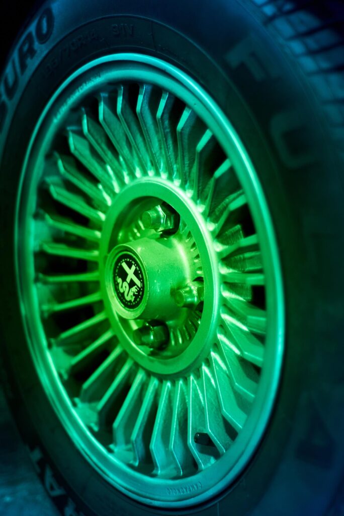 Detalle de llanta de radios metálicos de Alfa Romeo GT Junior iluminada en verde - fotografía Frameburn